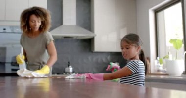 Mutlu çift ırklı anne ve kız mutfak atölyesini birlikte temizliyor, ağır çekimde. Annelik, çocukluk, birliktelik, temizlik, ev işleri, hijyen, ev hayatı ve yaşam tarzı, değişmemiş.