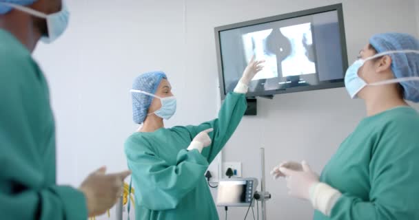 Diverse Weibliche Und Männliche Chirurgen Masken Diskutieren Operationssaal Über Röntgenbilder — Stockvideo