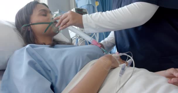 病院のベッドで多様な女性患者と女性医師が酸素マスクを着用し ゆっくりとした動きをしています 医療機器 変わらない — ストック動画