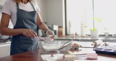 Çift ırklı kadın apronlu kek karıştırma, mutfakta pişirme, fotokopi alanı, ağır çekim. Yemek, yemek pişirme, ev hayatı ve yaşam tarzı, değişmemiş..