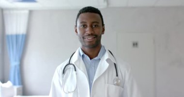 Hastanenin koğuşunda gülümseyen beyaz ceketli mutlu Afro-Amerikan erkek doktor portresi. Hastane, iş, ilaç ve sağlık hizmetleri, değiştirilmemiş.