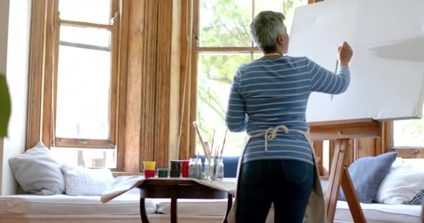 エプロンを着て 自宅で大きなキャンバスに絵を描いた上級女性 ゆっくりとした動き 国内生活 アート 引退生活 ライフスタイル — ストック動画