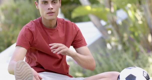 Homem Biracial Focado Sentado Com Futebol Tocando Dedos Jardim Ensolarado — Vídeo de Stock