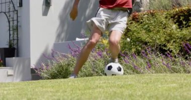 Güneşli bahçede futbol antrenmanı yapan düşük ırklı bir adam, yavaş çekim. Futbol, beceri, eğitim, yaz, antrenman, spor, spor ve sağlıklı yaşam tarzı, değişmemiş.