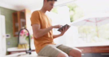 Güneşli bahçeye tablet tablet kullanan düşünceli bir çift ırklı adam. Kopya alanı, ağır çekim. İletişim, yaz, boş zaman, ev hayatı ve yaşam tarzı, değişmemiş.