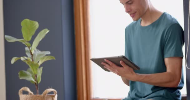 Güneşli Oturma Odasında Duran Tablet Kullanan Odaklanmış Çift Irklı Adam — Stok video