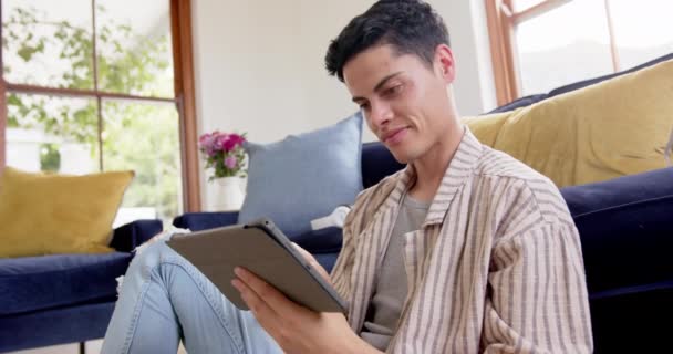 Homem Biracial Feliz Sentado Chão Usando Tablet Sala Estar Câmera — Vídeo de Stock