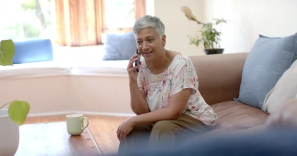 Ευτυχισμένη Ηλικιωμένη Γυναίκα Που Κάθεται Στον Καναπέ Και Μιλάει Smartphone — Αρχείο Βίντεο