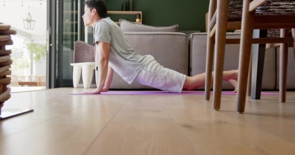 Fokuserad Biracial Man Praktiserar Yoga Liggande Vardagsrummet Slow Motion Cobra — Stockvideo