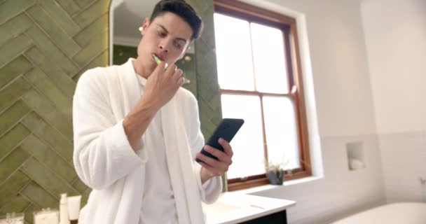 Pria Kelahiran Menggosok Gigi Dan Menggunakan Smartphone Kamar Mandi Pagi — Stok Video