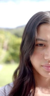 Güneşli bahçedeki mutlu melez genç kızın dikey portresi, fotokopi alanı, ağır çekim. Yaz, ergenlik, boş zaman, doğa, refah ve yaşam tarzı, değişmemiş..