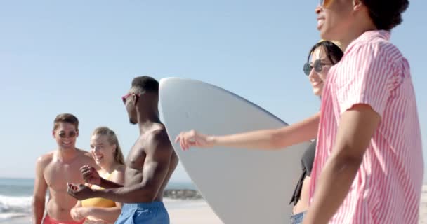 年轻的白人女人在海滩上和一个年轻的白人男人聊天 他们在户外享受着阳光灿烂的一天 身边有朋友和冲浪板 动作缓慢 — 图库视频影像