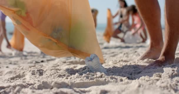 多様なボランティアが砂浜でゴミを集め コピースペースを設けています クリーンアップ活動は 環境への意識とコミュニティの関与 遅い動きを強調しています — ストック動画