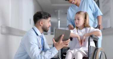 Doktor, hastanede genç beyaz bir kızla fotokopi odası hakkında konuşuyor. Hemşire bir tablet üzerinde yoğunlaşırken yardımcı olur, sağlık ve hasta etkileşimlerini vurgular, yavaş çekimde.