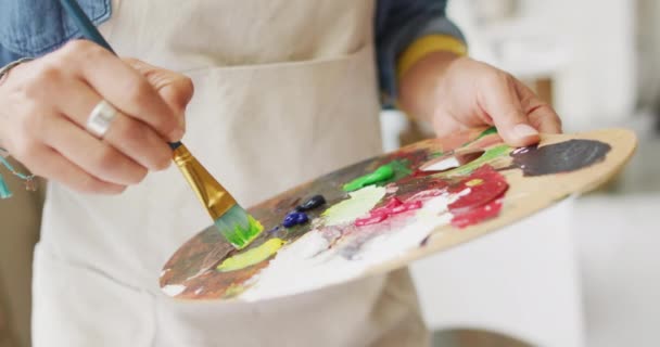예술가는 공간과 집에서 팔레트에 페인트를 믹스합니다 클로즈업 창조적 프로세스의 본질을 — 비디오