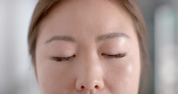一个年轻的亚洲女人的脸的特写 有复制的空间 她的表情是中性的 背景模糊 动作缓慢 — 图库视频影像