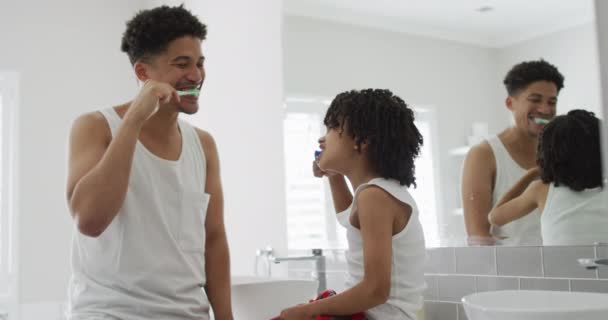 父亲和儿子在家里一起刷牙 在明亮的浴室里 他们在早上的例行公事中分享着一个亲密的时刻 动作缓慢 — 图库视频影像