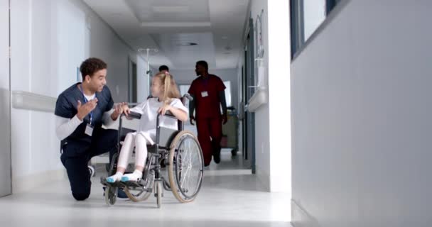 Jovem Enfermeira Birracial Ajuda Uma Menina Caucasiana Uma Cadeira Rodas — Vídeo de Stock