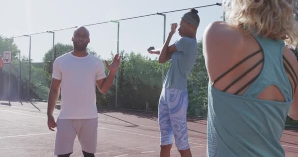 Biracial Manは屋外バスケットボールコートで戦略を議論している チームメイトは 晴れた 屋外の設定 スローモーションでゲームのために準備するように意図的に聞きます — ストック動画