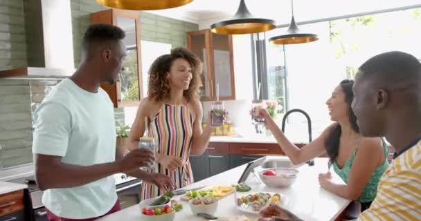 不同的朋友在明亮的家庭厨房里敬酒 他们在一起做饭的时候分享着快乐的时刻 慢动作 — 图库视频影像