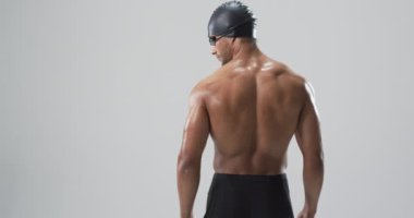 Atletik çift ırklı atlet yüzücü yüzmeye hazır, fotokopi alanı da var. Dengeli duruşu bir yarıştan önce odaklanmayı ve kararlılığı gösteriyor, ağır çekim..