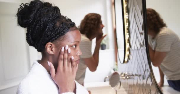 多样化的夫妇 年轻的非洲裔美国女人和年轻的白人男人在浴室里 他们每天早上都参加护肤活动 这反映了他们共同的家庭生活 缓慢的运动 — 图库视频影像