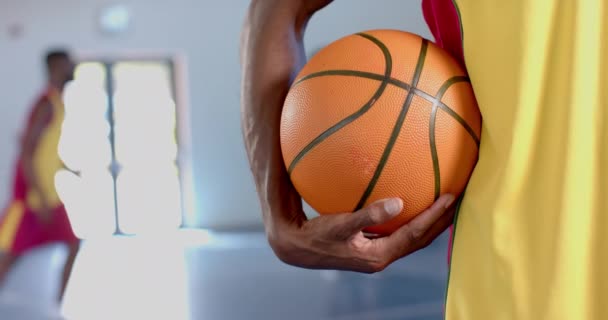 Крупный План Баскетбольного Мяча Удерживаемого Афроамериканцем Обстановка Предполагает Баскетбольную Игру — стоковое видео