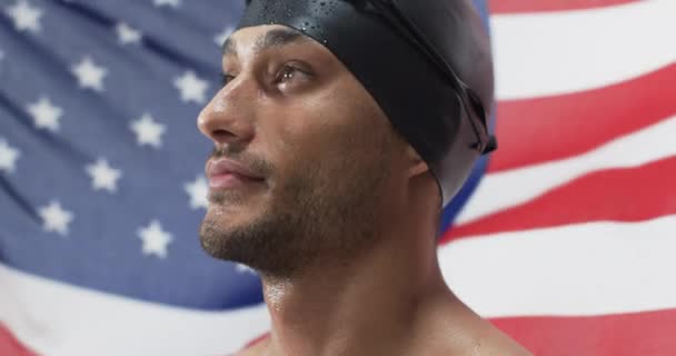 身穿泳衣的年轻运动员自信地摆出姿势 他的表情和美国国旗的背景暗示着一个爱国心的运动员主题 慢动作 — 图库视频影像