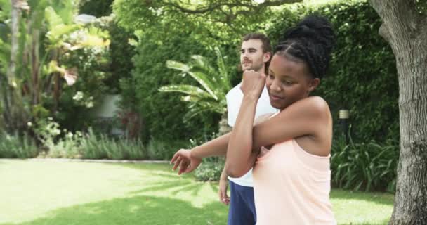 年轻的非洲裔美国妇女和年轻的白人男子喜欢户外活动 他们全神贯注地在一个繁茂的花园里做着他们的日常健身活动 动作缓慢 — 图库视频影像