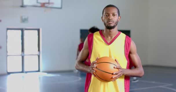 非裔美国人在体育馆里打篮球 他的队友在后台表演 强调团队精神 运动精神和慢动作 — 图库视频影像