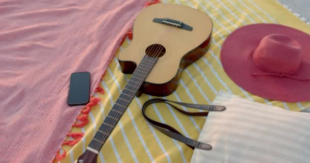 Гитара Лежит Рядом Шляпой Телефоном Пляжном Одеяле Пляжные Развлечения Создают — стоковое видео