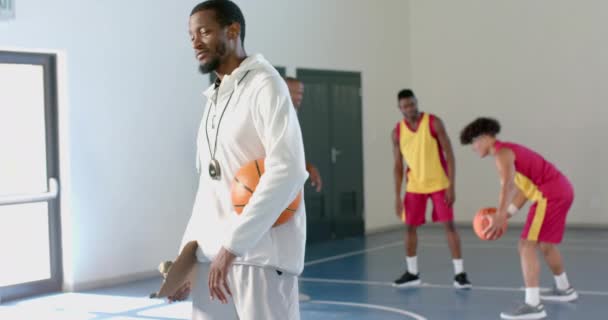 Afroamerykanin Pozuje Pewnie Siłowni Wyróżnia Się Jako Trener Koszykówką Nadzorujący — Wideo stockowe