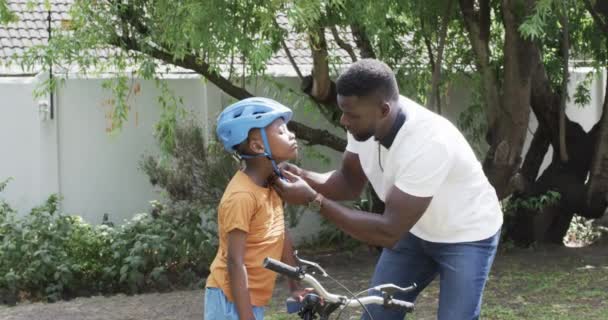 Afroamerykanin Ojciec Pomaga Synowi Kask Rowerowy Zewnątrz Bezpieczeństwo Przede Wszystkim — Wideo stockowe