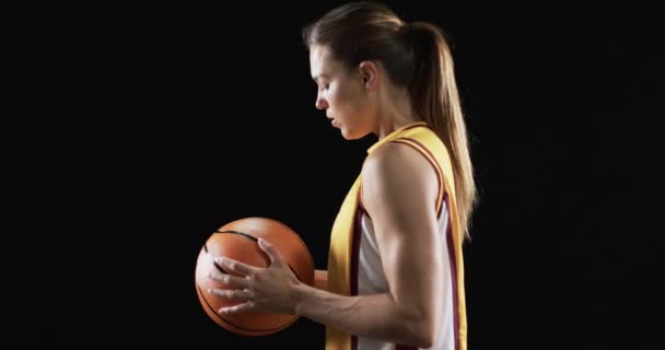专注的白人年轻女子在黑暗的背景下 在黑色背景下打篮球 在赛前表现出激情和专注 动作缓慢 — 图库视频影像