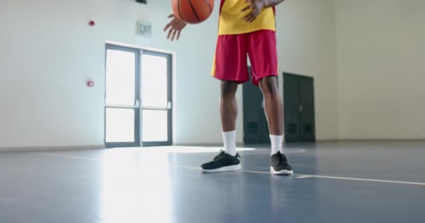 年轻的非裔美国人在体育馆里打篮球 运动服暗示他已经准备好参加比赛或练习 慢动作 — 图库视频影像