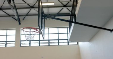 Spor salonunda, fotokopi alanı olan kapalı basketbol potası. Havanın ortasındaki bir basketbol topu, bir okulda ya da eğlence tesisinde devam eden bir oyun ya da antrenman oturumunu önerir..