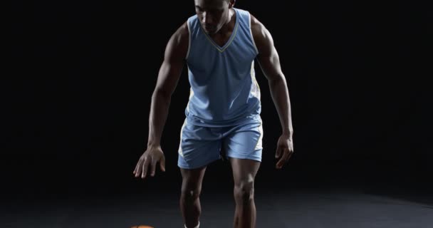 非洲裔美国篮球运动员在一个黑色背景上摆出一个专注的姿势 当他准备在黑暗 缓慢的运动中参加比赛时 他的决心是显而易见的 — 图库视频影像