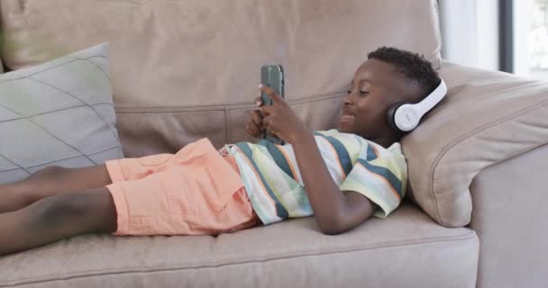 Chico Afroamericano Disfruta Música Casa Está Relajando Sofá Con Auriculares — Vídeo de stock