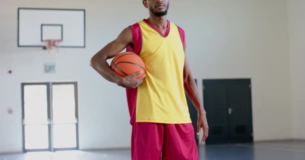 非洲裔美国人自信地在体育馆里摆姿势 并留有复制的空间 他的运动服表明 他已经准备好参加篮球赛或训练课 动作缓慢 — 图库视频影像