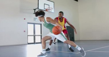 Genç Afro-Amerikalı erkekler kapalı mekanlarda basketbol oynarlar, fotokopi alanlarıyla. Atletizm ve takım çalışması spor salonundaki maçtan keyif alırken yavaş çekimde parlıyor..