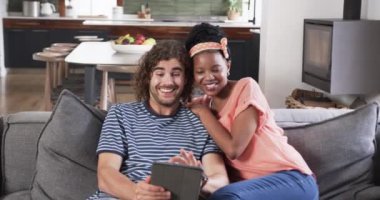 Çeşitli çiftler rahat bir evde tablet yemekten hoşlanırlar. Kanepede bir anlık dijital eğlence paylaşıyorlar, modern eğlenceyi yansıtıyorlar, yavaş çekim..