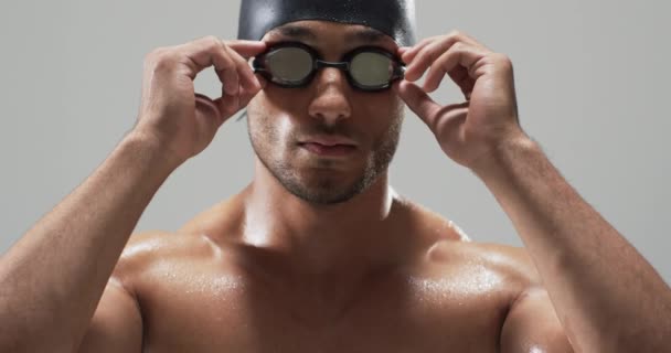 レース前にゴーグルを調整する集中水泳選手 彼の激しい視線は スポーツの決意とプロフェッショナリズム ゆっくりとした動きを示唆しています — ストック動画