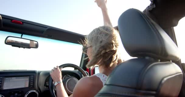 若い白人女性は 道路旅行でコンバーチブルでドライブを楽しんでいます 彼女の手は空中で育ち オープンロードの自由の本質を捉え ゆっくりと動く — ストック動画