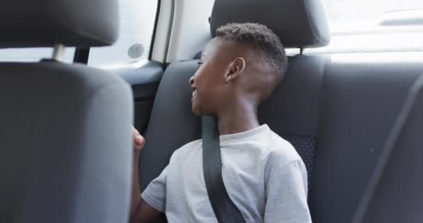 アフリカ系アメリカ人の少年は バックシートに座っている間 車に乗って笑顔とジェスチャーを楽しんで 喜びの瞬間を示しています 遅い動き — ストック動画