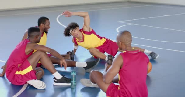多样化的篮球队在球场上休息一下 在他们休息的过程中 玩家们会进行热烈的讨论 分享他们的策略和结合 以及慢动作 — 图库视频影像