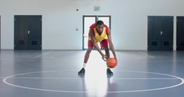 アフリカ系アメリカ人は屋内でバスケットボールをしている 明るい体育館でゲームに焦点を当てています スローモーション — ストック動画