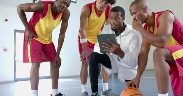 多样化篮球队评审策略 在室内场地暂停时 运动服的玩家将注意力集中在数字平板电脑上 动作缓慢 — 图库视频影像
