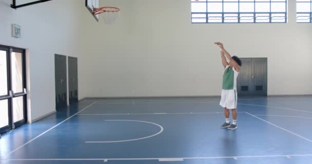 Joven Birracial Juega Baloncesto Interior Está Enfocado Anotar Gimnasio Escolar — Vídeo de stock