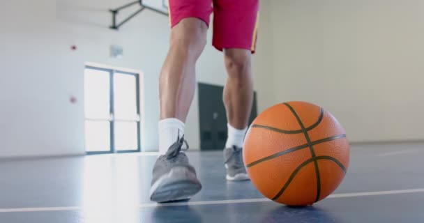スポーツ選手はジムでバスケットボールをする準備ができています プレーヤーの靴やボールに焦点を当てることは ゲームの準備 スローモーションを強調しています — ストック動画