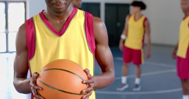 Συγκεντρωμένος Αφροαμερικάνος Που Κρατάει Ένα Μπάσκετ Ένα Γυμναστήριο Συμπαίκτες Είναι — Αρχείο Βίντεο
